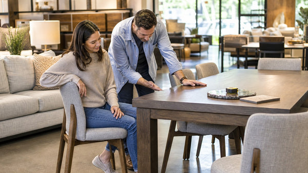 Couple reviewing size, shape, and finish before choosing a dining table in a Victoria showroom